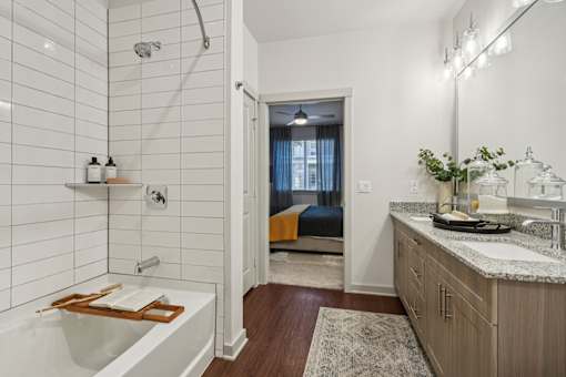 A bathroom with a white tub and a sink with a plant on the counter.