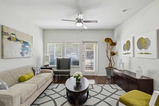 A living room with a beige couch, a coffee table, and a ceiling fan.