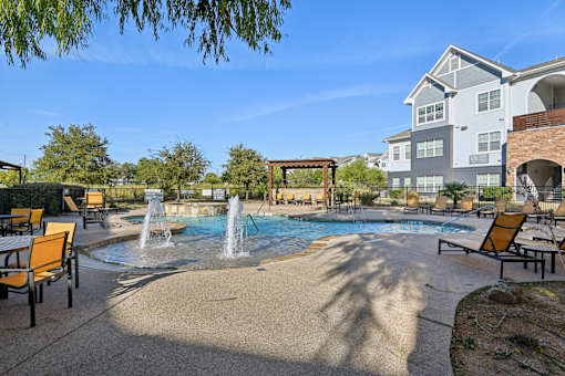 A pool area with a waterfall and lounge chairs.