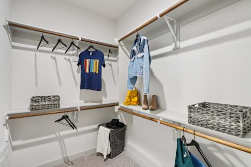 A white closet with clothes and shoes on shelves and hangers.