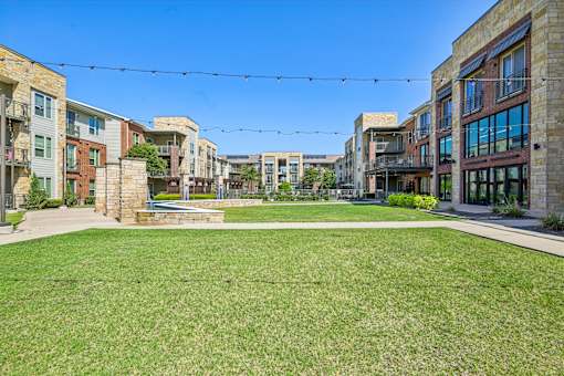 A sunny day in a residential area with a grassy lawn and apartment buildings.
