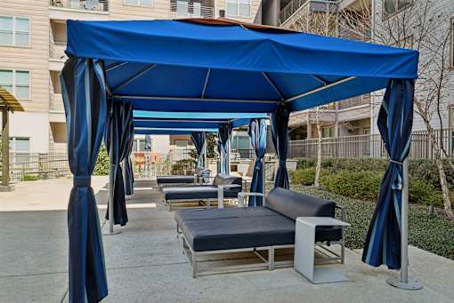 A blue canopy with curtains and a bench underneath it.