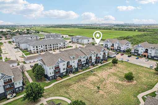 A bird's eye view of a residential area with apartment buildings and a large open field.