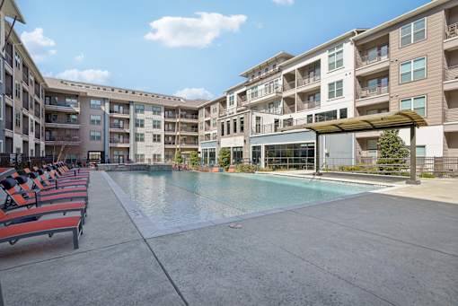 A large swimming pool is surrounded by apartment buildings.