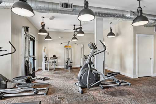 A gym with a variety of equipment including a stationary bike, treadmill, and weights.
