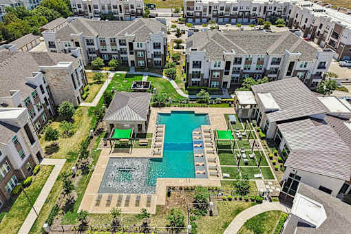 An aerial view of apartment buildings with a pool in the foreground.