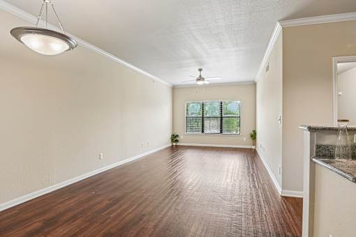 A spacious room with wooden floors and a ceiling fan.
