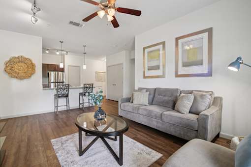 A living room with a grey couch, a coffee table, and a ceiling fan.