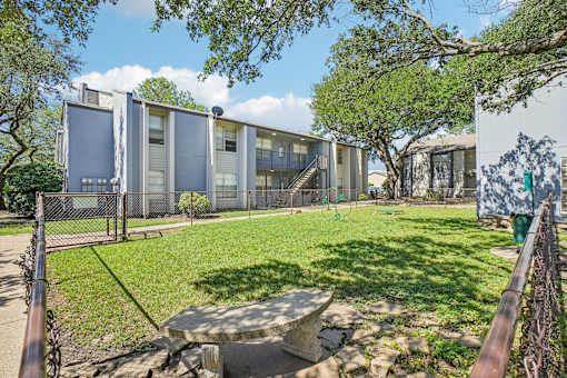 A modern building with a fence and a green lawn in front.