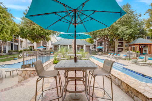 a patio with tables and umbrellas next to a swimming pool