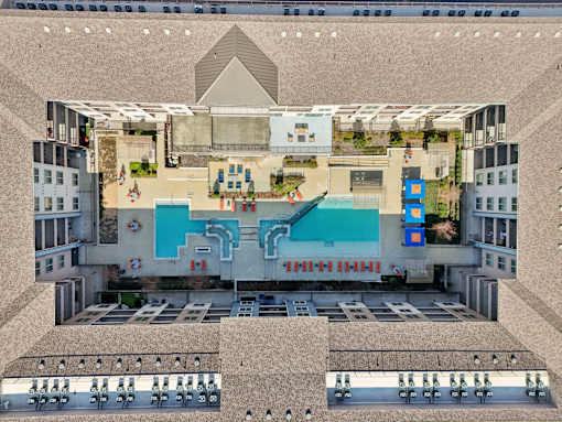 A top-down view of a building with a pool and a large open area with people sitting on chairs.