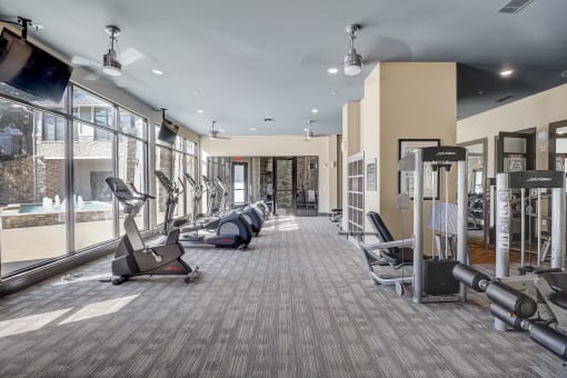 a gym with treadmills and other exercise equipment in a building with large windows