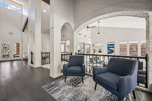 A spacious lobby with two chairs and a patterned rug.