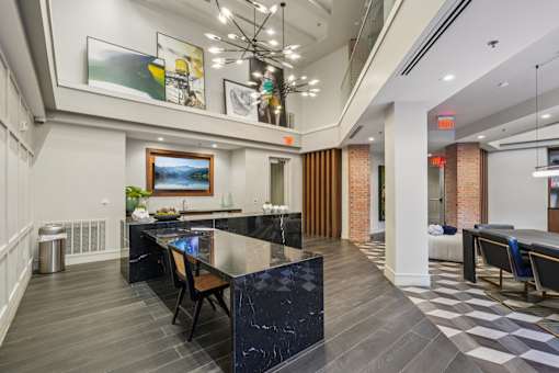 A modern kitchen with a black marble island and a dining table with chairs.