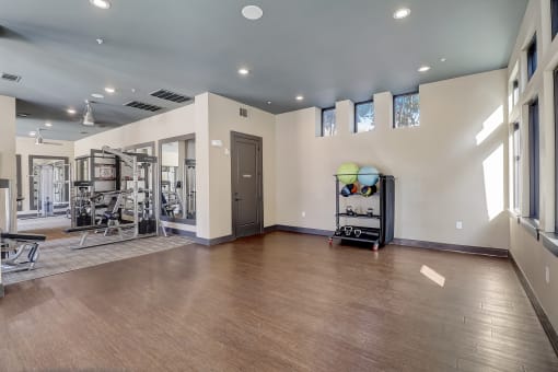 a workout room with a treadmill and weights on a wooden floor
