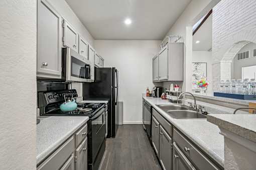 A kitchen with black appliances and white cabinets.