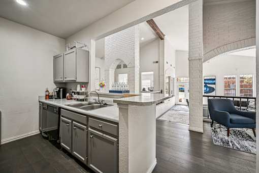 A modern kitchen with a large island and a blue chair in the living room.
