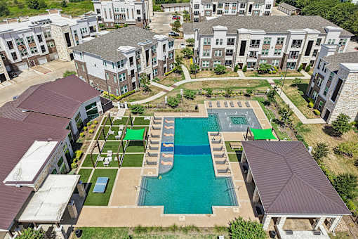 An aerial view of apartment buildings with a pool in the foreground.