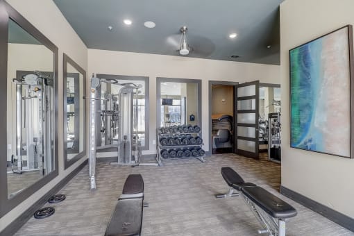 a fitness room with cardio machines and a large painting on the wall