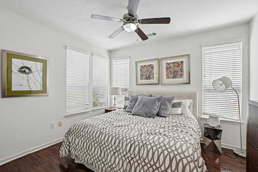 A bedroom with a patterned bedspread and a ceiling fan.