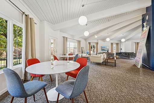 A white round table with four chairs around it in a room with a white ceiling.