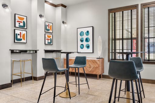 a bar area with stools and tables and artwork on the wall