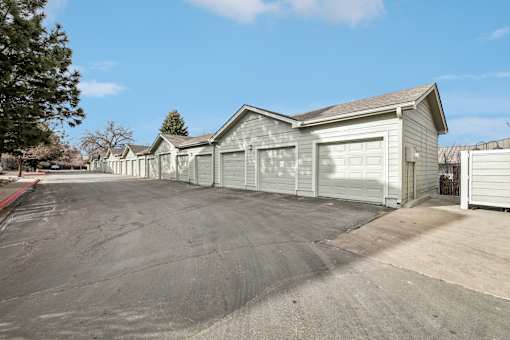 A long row of houses with garages are lined up on a street.