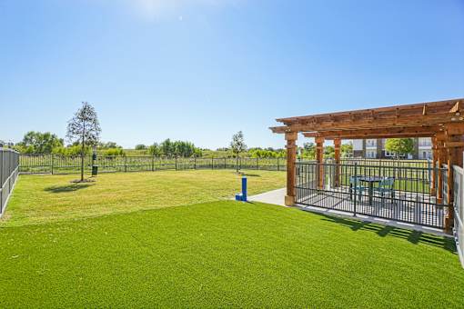 A sunny day at a park with a wooden structure and a fence.