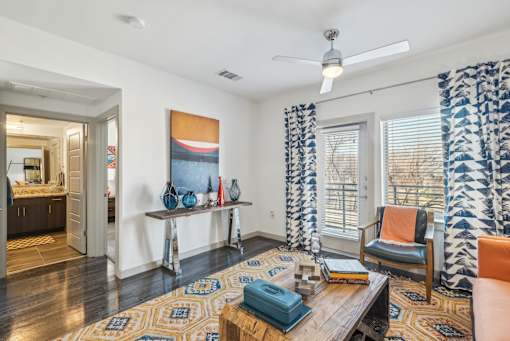 A living room with a rug, a chair, a table, and a painting on the wall.