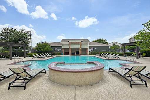 A pool with lounge chairs around it.