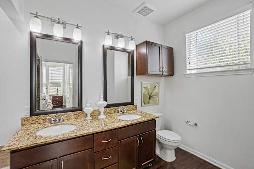 A bathroom with a granite countertop and a large mirror above it.