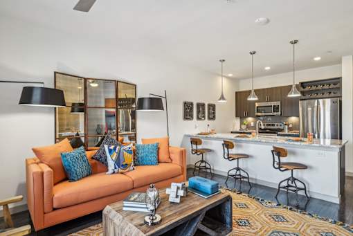 A modern living room with a kitchen in the background.