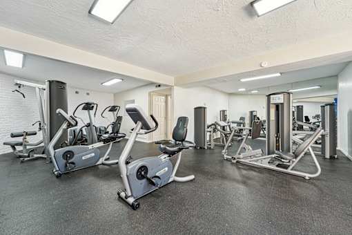 A gym with a variety of exercise equipment including treadmills, stationary bikes, and weight machines.