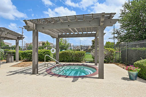A pool under a pergola in a sunny backyard.