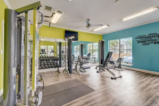 a gym with weights and cardio equipment and a window