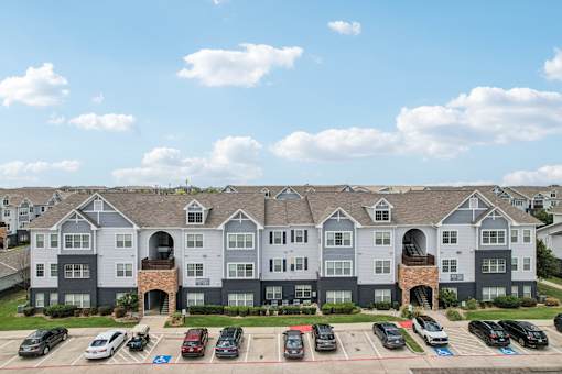 A large apartment complex with a parking lot in front.
