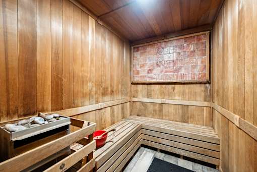 A wooden sauna with benches and a bucket of stones.