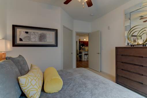 A bedroom with a bed, two pillows, a ceiling fan, and a mirror.