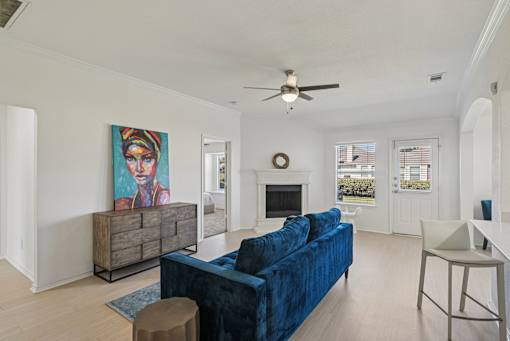 A living room with a blue couch and a painting on the wall.