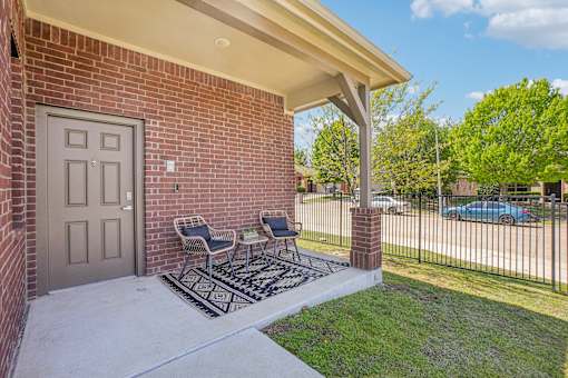 A house with a grey door and a small porch with two chairs.