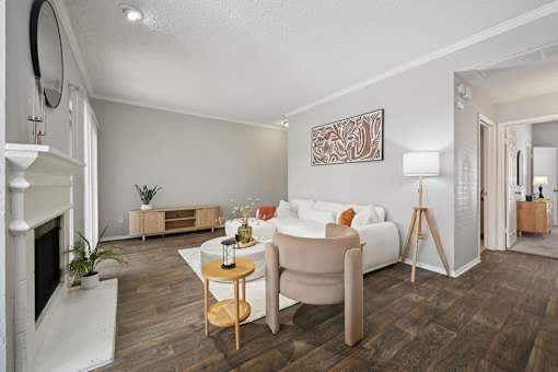 A living room with a white couch, a fireplace, and a painting on the wall.