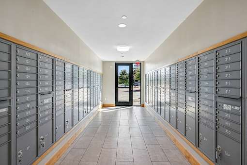 A long hallway with mailboxes on both sides and a door at the end.