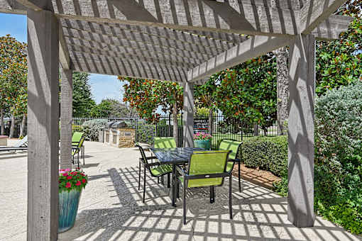 A patio with a table and chairs under a pergola.