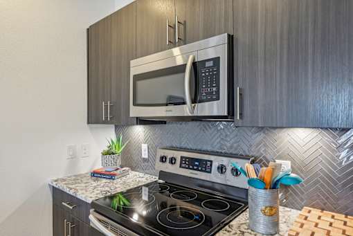 A modern kitchen with a stainless steel oven and microwave above it.
