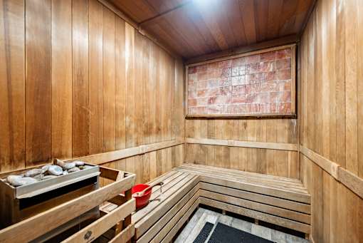 A wooden sauna with benches and a bucket of stones.