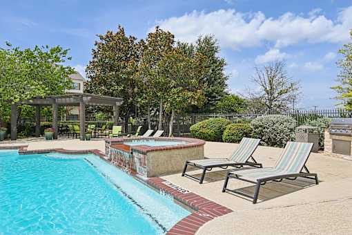 A pool with a red brick border and striped lounge chairs.