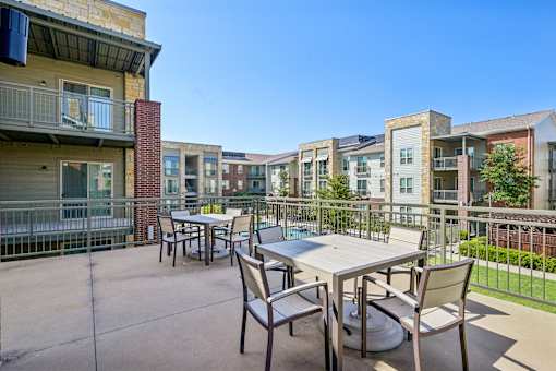 A patio with a table and chairs is surrounded by apartment buildings.