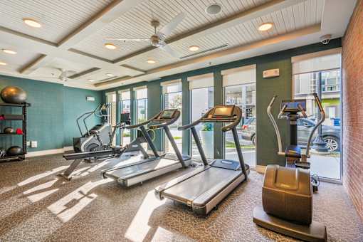 A gym with treadmills, elliptical machines, and a weight bench.