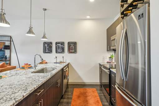 A modern kitchen with a marble countertop and stainless steel appliances.