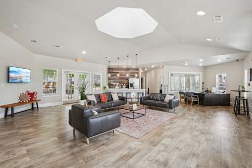 A spacious living room with a variety of seating options and a flat-screen TV mounted on the wall.